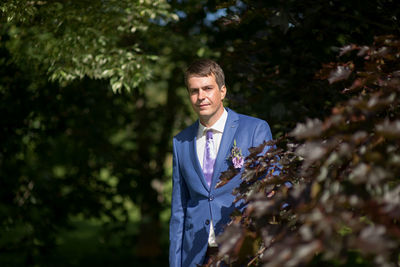 Portrait of bridegroom by plant at park