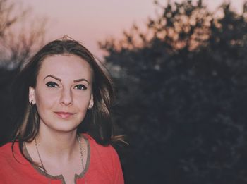 Portrait of mid adult woman standing against trees during sunset