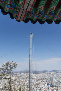 Tower and roof overlooking cityscape against blue sky