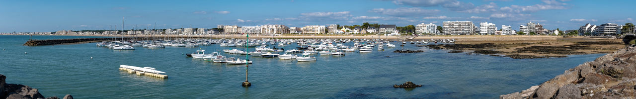 Sailboats moored in sea against sky