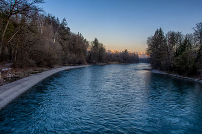 River amidst trees against sky during sunset