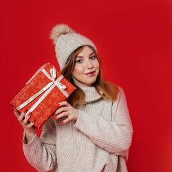 Portrait of a smiling young woman against red background