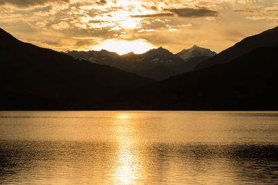 Idyllic shot of river and mountains against sky during sunset