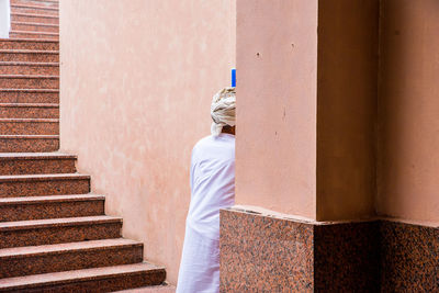 Rear view of man standing on staircase of building