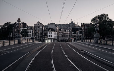 Railroad tracks in city against clear sky