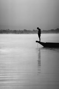Side view of silhouette man on lake against sky