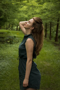 Side view of young woman standing in forest