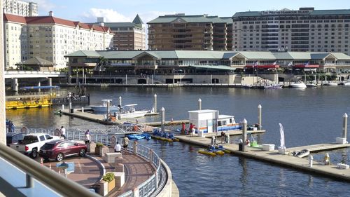 High angle view of sailboats moored on river by buildings in city