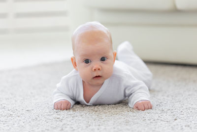 Portrait of cute baby boy lying on floor