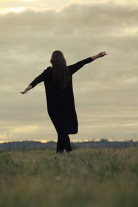Surface level view of woman with arms outstretched on grassy field