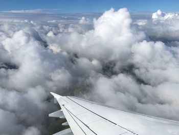 Aerial view of airplane wing against cloudy sky