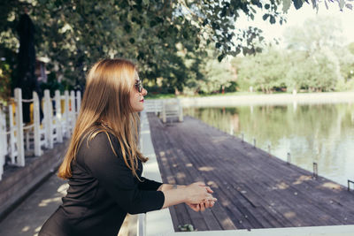 Side view of young woman standing by lake