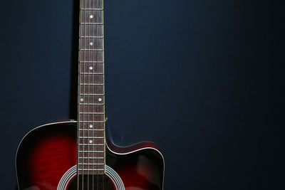 Close-up of acoustic guitar against black background
