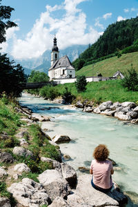 Rear view of woman sitting at riverbank