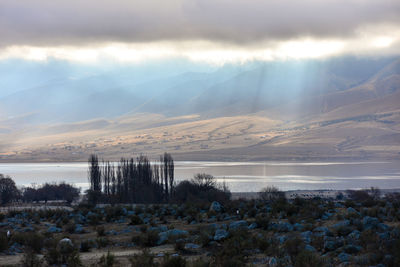 Sunlight streaming through clouds on river and mountains