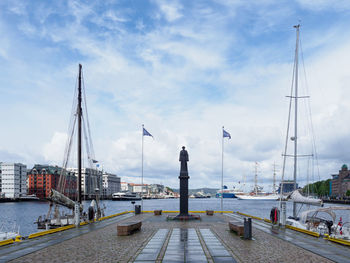 Sailboats moored at harbor against sky