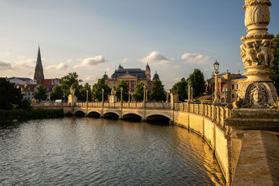 Arch bridge over river against buildings in city