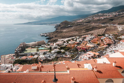Aerial view of townscape by sea against sky