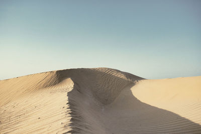 Sand dune in desert against clear sky