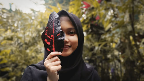 Portrait of beautiful young woman holding plant