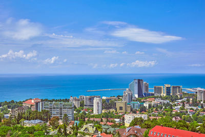 Buildings by sea against blue sky