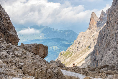 Rocky mountain canyon with a scenic view to a valley in the alps with a mountain wanderer