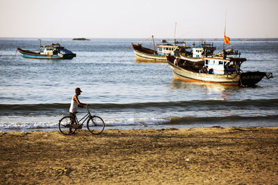 Man on bicycle at beach against sky