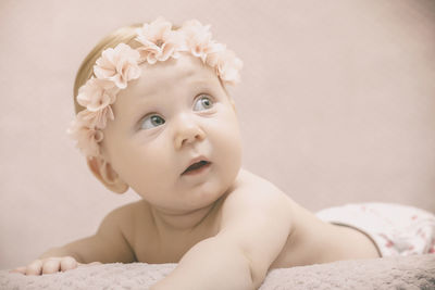 Close-up of cute baby girl wearing tiara lying on bed