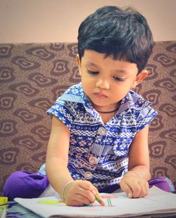 Cute girl coloring in book at home
