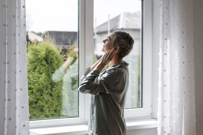 Mature woman standing at the window at home