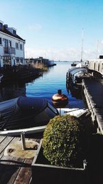 Boats moored at harbor by city against sky