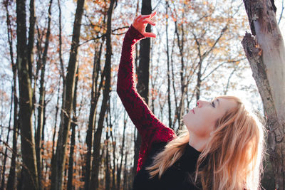 Side view of young woman against trees in park