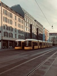 Railroad tracks by buildings in city against sky