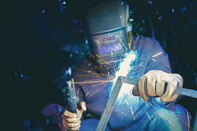 Low angle view of man welding metal at night