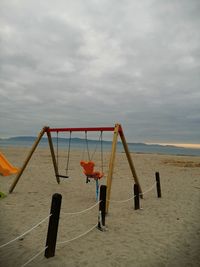 Deck chairs on beach against sky