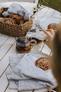 Woman's hand pouring milk into black coffee