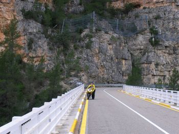 Woman with motorcycle on bridge by rocky mountains