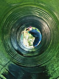 Portrait of boy looking through rusty pipe