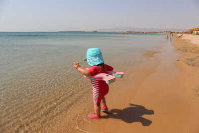 Full length of girl standing at beach against sky