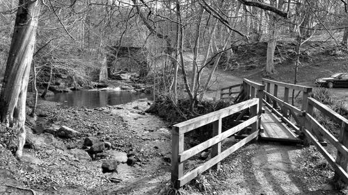 Footbridge over river amidst trees during winter