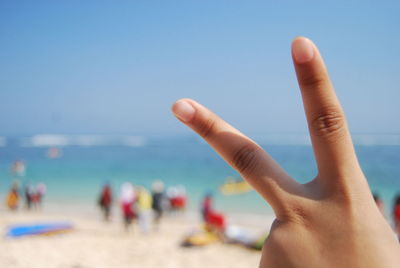 Midsection of person at beach against sky