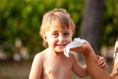 Portrait of shirtless boy holding baby outdoors