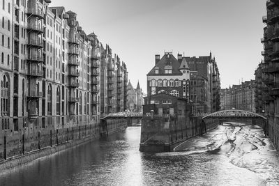 Bridge over river against buildings in city