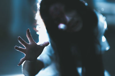 Close-up of spooky woman reaching in darkroom