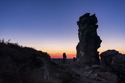 Rock formations on silhouette land against sky during sunset