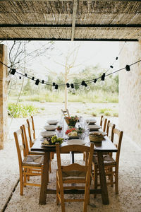 Dining table with chairs and plates arranged at patio in backyard