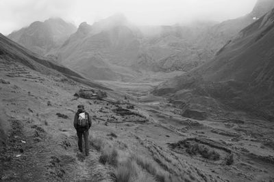 Rear view of woman walking on mountain against sky