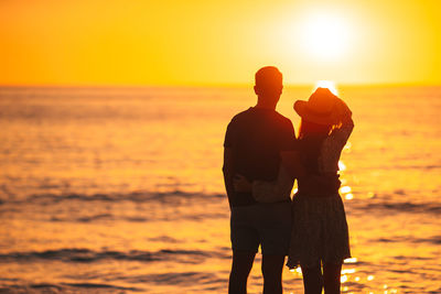 Silhouette woman standing at beach during sunset