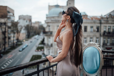 Side view of young woman standing on bridge in city