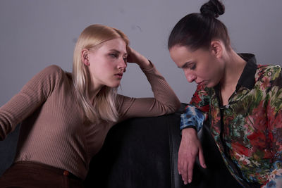 Side view of young woman looking away against wall at home